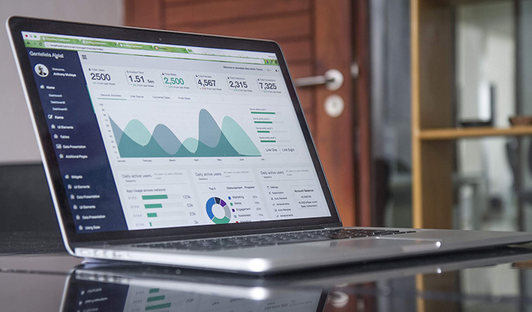 An open laptop displays charts and graphs.