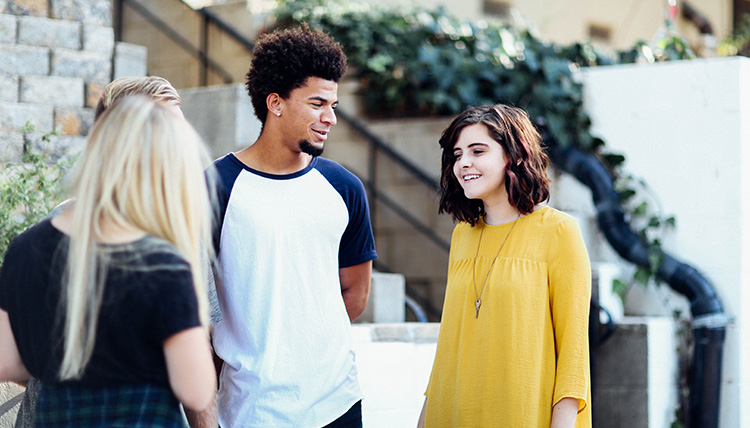 Three young people talk outside.