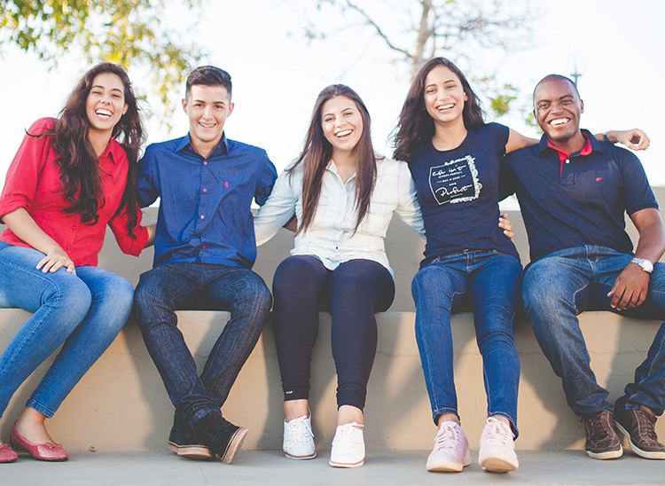 A group of young people sit together and smile.