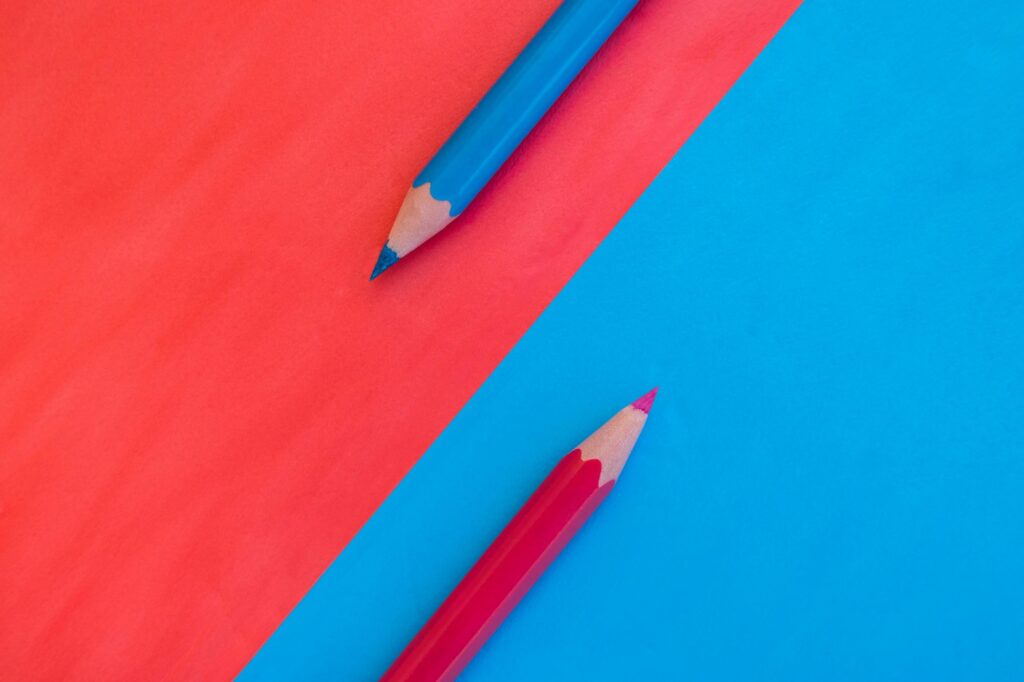 Red colored pencil on blue background and blue colored pencil on red background